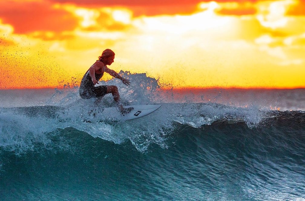 A surfer turning on a wave at Cerritos as the sun goes down