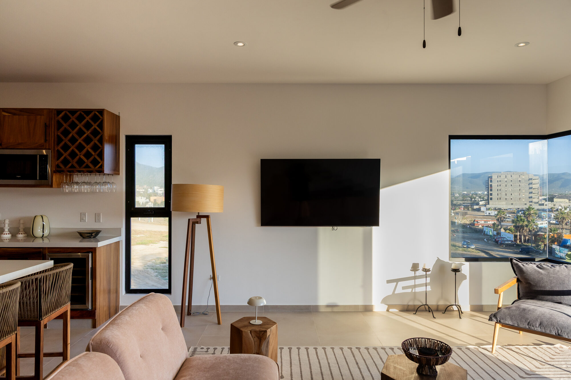 The living area with a corner window and a floor lamp in late afternoon light