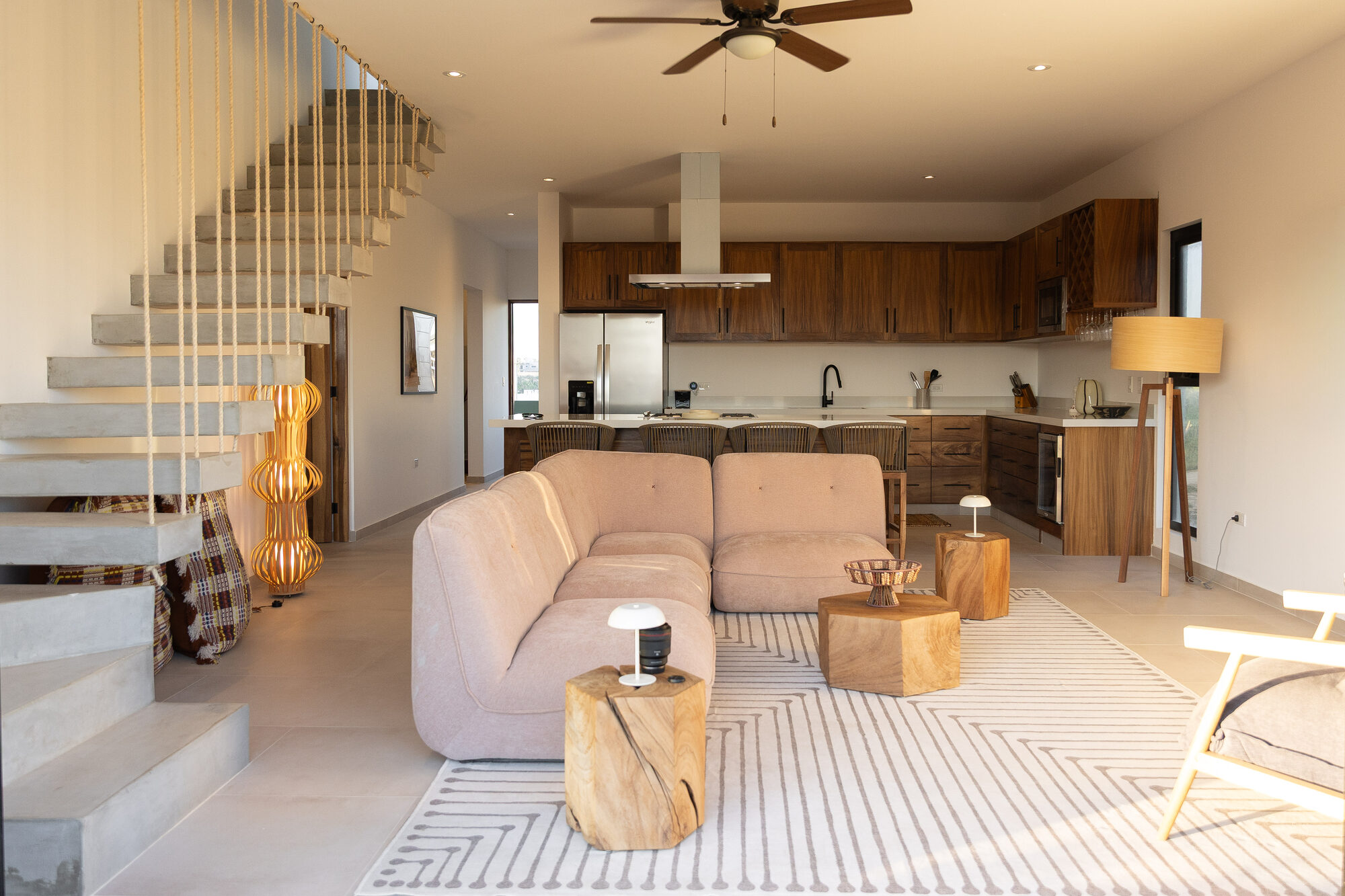 Wide view of the open living and kitchen space with wooden cabinetry and a rising stair